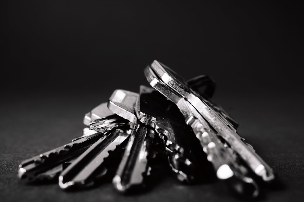 about-us-01 A close-up shot of a pile of metallic keys on a dark surface, emphasizing security and precision.