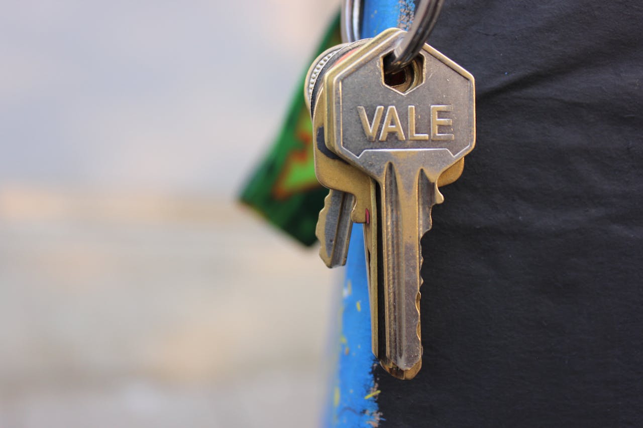 about-us-02 A detailed view of a metallic key with Vale engraved on it, hanging against a blurred background.